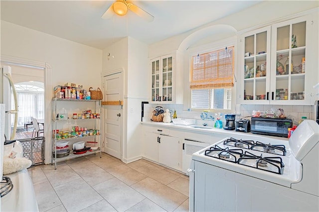 kitchen featuring white gas range, decorative backsplash, a ceiling fan, black microwave, and light tile patterned flooring