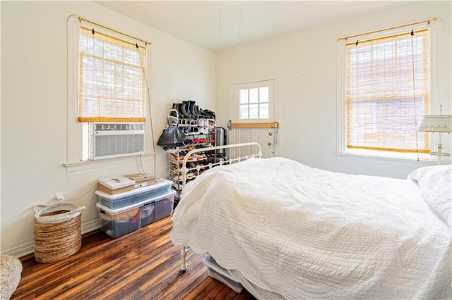 bedroom featuring baseboards, wood finished floors, and cooling unit