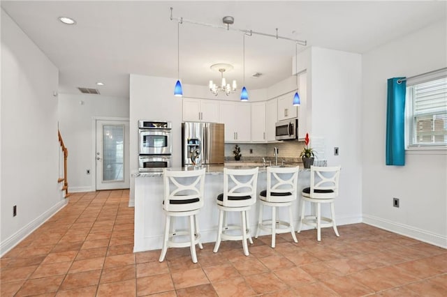 1091 Marina Dr, Slidell, LA 70458 - kitchen with visible vents, a notable chandelier, appliances with stainless steel finishes, a peninsula, and decorative backsplash
