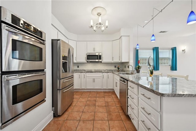 1091 Marina Dr, Slidell, LA 70458 - kitchen with an inviting chandelier, a sink, a peninsula, stainless steel appliances, and decorative backsplash