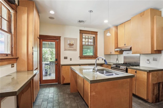 2227 Wirth Pl, New Orleans, LA 70115 - kitchen with stainless steel gas stove, visible vents, under cabinet range hood, a kitchen island with sink, and a sink