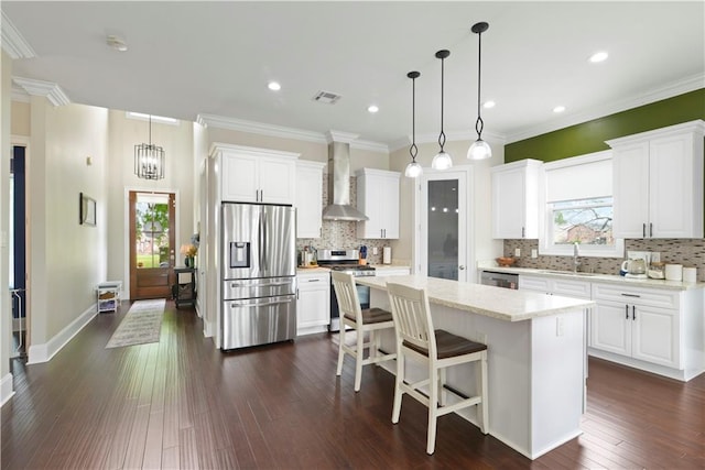85 W Claiborne Sq, Chalmette, LA 70043 - kitchen featuring visible vents, dark wood-style flooring, wall chimney range hood, appliances with stainless steel finishes, and a kitchen island