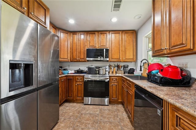 kitchen featuring visible vents, a sink, appliances with stainless steel finishes, brown cabinets, and recessed lighting