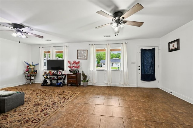 living area featuring ceiling fan, baseboards, visible vents, and a wealth of natural light