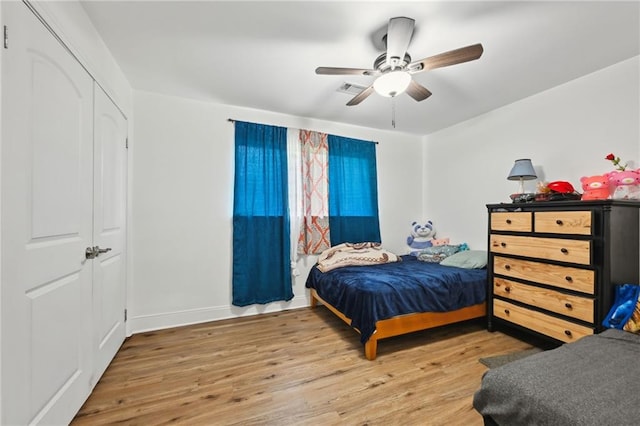 bedroom featuring visible vents, a closet, baseboards, ceiling fan, and wood finished floors