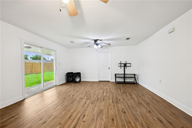 empty room with visible vents, baseboards, a ceiling fan, and wood finished floors