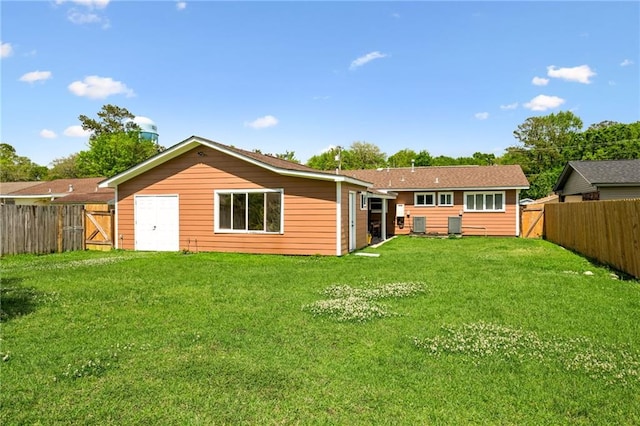 back of property with a fenced backyard, a gate, and a lawn