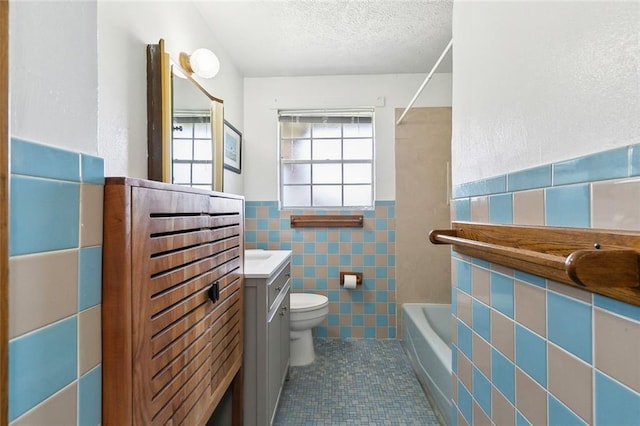 2344 Mississippi Ave, Metairie, LA 70003 - bathroom with tile walls, toilet, a textured ceiling, vanity, and tile patterned floors