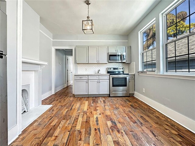 165355 Treasure St, New Orleans, LA 70119 - kitchen featuring appliances with stainless steel finishes, gray cabinets, hardwood / wood-style flooring, and decorative backsplash