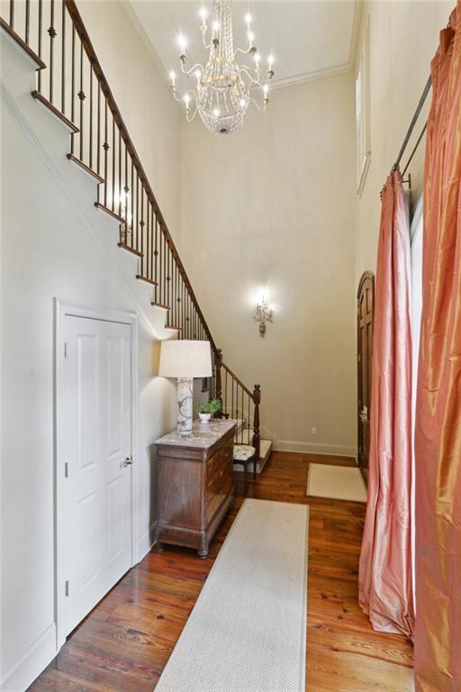 519 Homestead Ave, Metairie, LA 70005 - entrance foyer with baseboards, a chandelier, a high ceiling, stairs, and wood finished floors