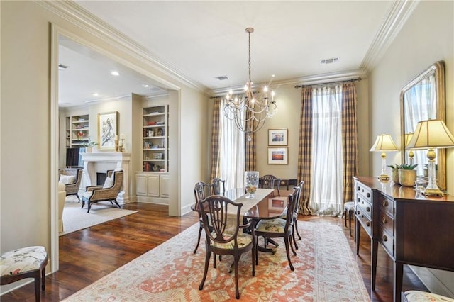 519 Homestead Ave, Metairie, LA 70005 - dining space with visible vents, built in features, a notable chandelier, crown molding, and wood finished floors