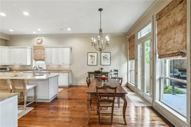 519 Homestead Ave, Metairie, LA 70005 - kitchen featuring white cabinets, a notable chandelier, a sink, crown molding, and wood finished floors