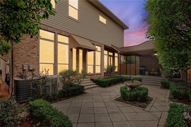 519 Homestead Ave, Metairie, LA 70005 - back of house at dusk with brick siding, a patio area, and central AC