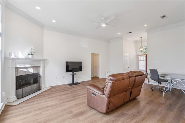 living room featuring crown molding, light wood finished floors, a ceiling fan, and visible vents