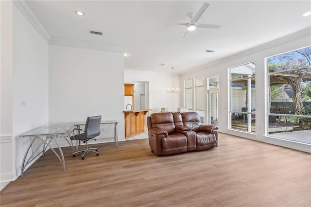 living area with crown molding, light wood finished floors, visible vents, and ceiling fan with notable chandelier