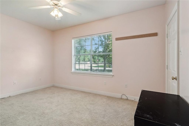carpeted empty room featuring baseboards and a ceiling fan