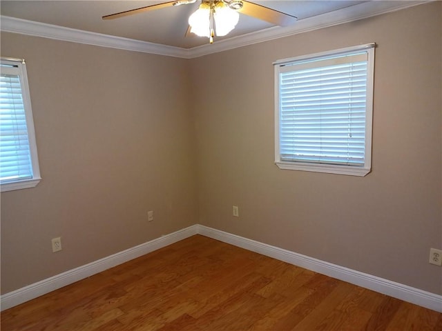 spare room with crown molding, ceiling fan, wood finished floors, and baseboards