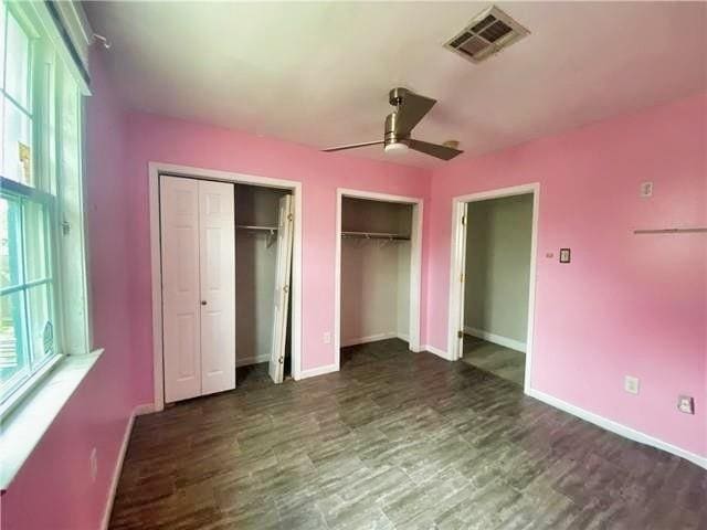 2359 Prentiss Ave, New Orleans, LA 70122 - unfurnished bedroom with visible vents, multiple windows, two closets, and wood finished floors