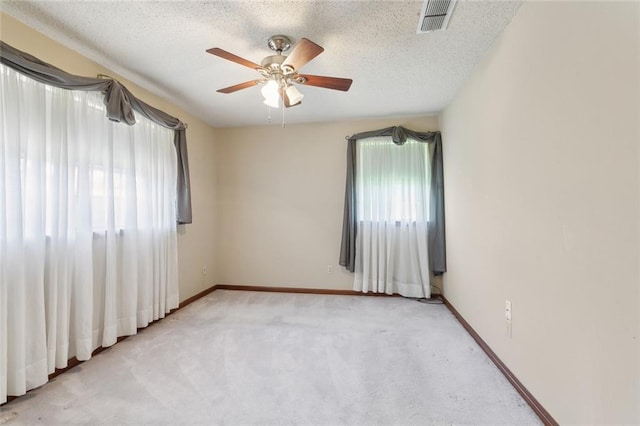 carpeted spare room with a ceiling fan, baseboards, visible vents, and a textured ceiling