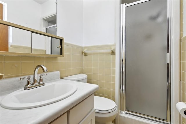 full bathroom with vanity, tile walls, a shower stall, and toilet