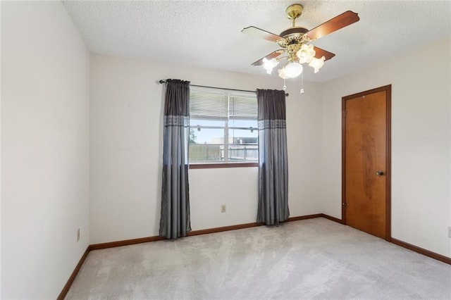 spare room with a ceiling fan, a textured ceiling, and light colored carpet