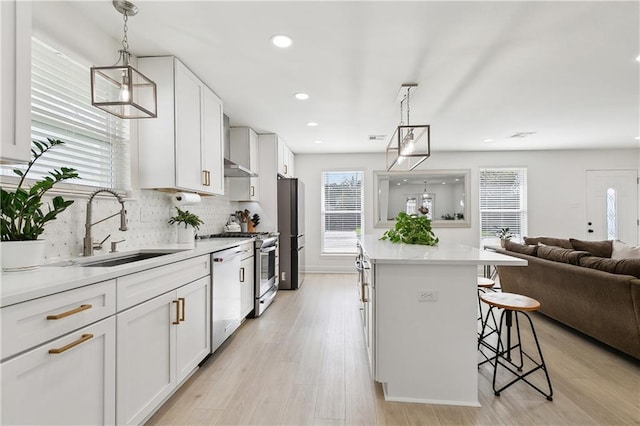 kitchen featuring stainless steel appliances, a sink, open floor plan, white cabinetry, and a breakfast bar