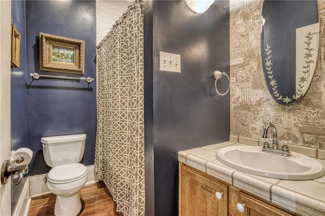 bathroom with vanity, a shower with curtain, toilet, wood finished floors, and baseboards