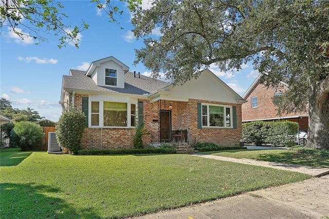 view of front facade featuring brick siding, a front yard, and central air condition unit