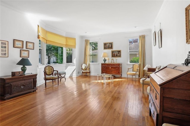 living area featuring baseboards, hardwood / wood-style flooring, and ornamental molding