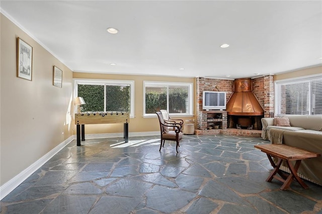 sitting room featuring baseboards, stone tile floors, crown molding, and recessed lighting