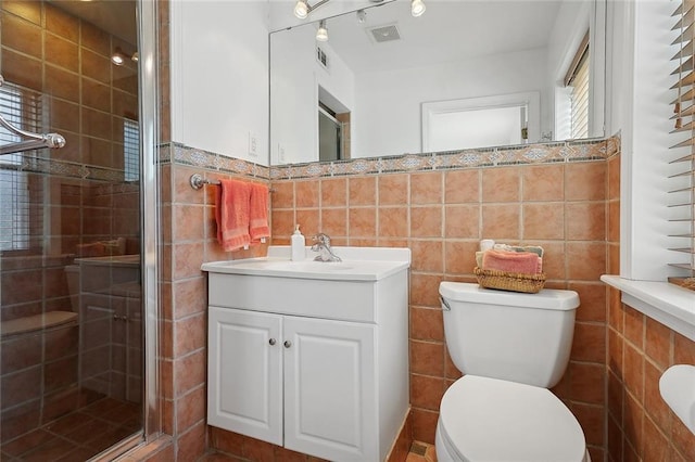 bathroom featuring toilet, tile walls, visible vents, a shower stall, and vanity