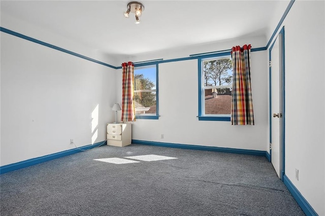 spare room with baseboards and carpet flooring
