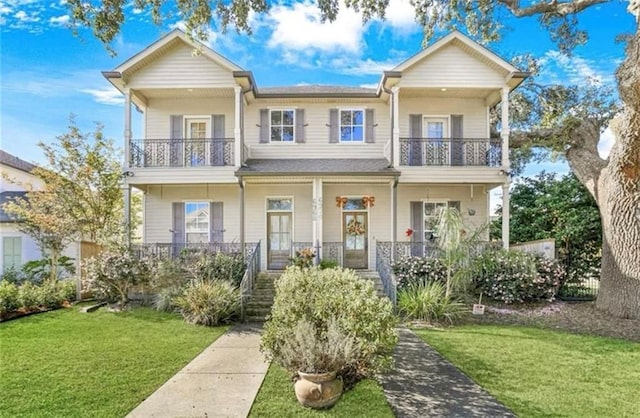 view of property featuring a porch, a front lawn, and a balcony