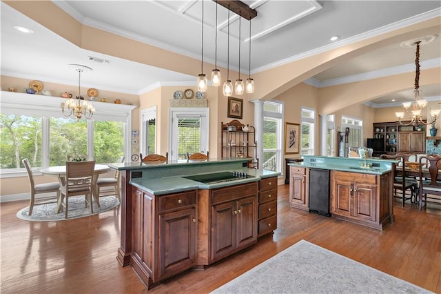 kitchen with an inviting chandelier, a kitchen island, visible vents, black electric cooktop, and wood-type flooring
