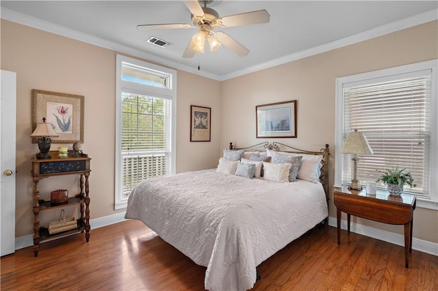 bedroom featuring visible vents, baseboards, crown molding, and wood finished floors