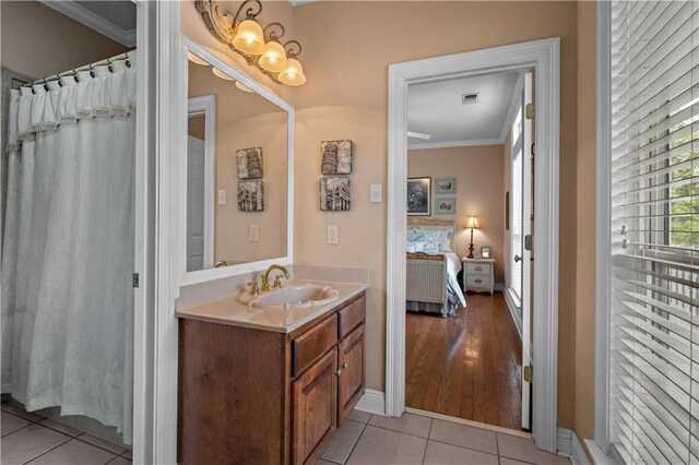 full bath with a notable chandelier, ornamental molding, connected bathroom, vanity, and tile patterned flooring