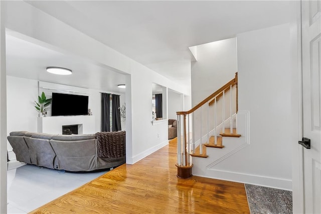 living area featuring wood finished floors, a fireplace, baseboards, and stairway