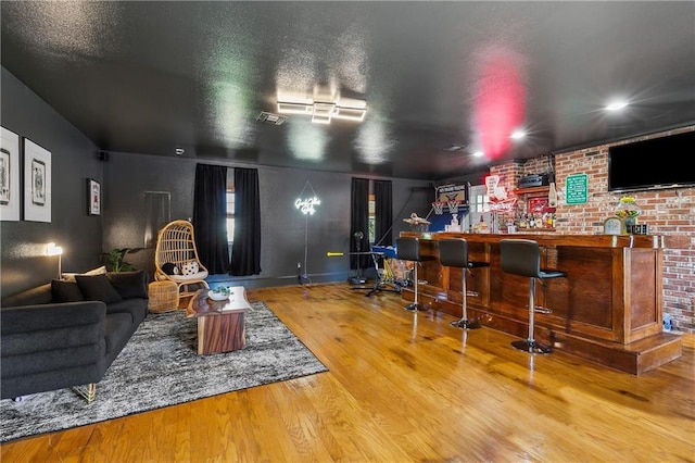cinema with a bar, visible vents, a textured ceiling, and wood finished floors