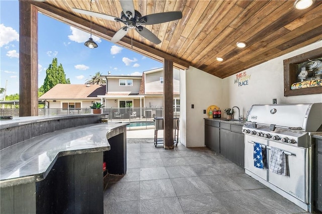 view of patio / terrace featuring a grill, a sink, ceiling fan, fence, and an outdoor kitchen