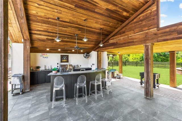 kitchen with a wealth of natural light, high vaulted ceiling, a breakfast bar, and wood ceiling