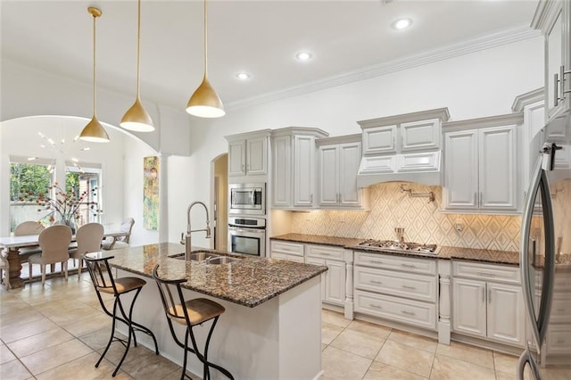 809 S Corniche Du Lac, Covington, LA 70433 - kitchen featuring appliances with stainless steel finishes, arched walkways, tasteful backsplash, dark stone countertops, and light tile patterned floors