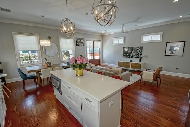 kitchen with dark wood-style flooring, ornamental molding, and visible vents