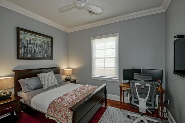 bedroom featuring baseboards, ornamental molding, visible vents, ceiling fan, and wood finished floors