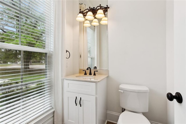 half bath featuring toilet, a chandelier, and vanity