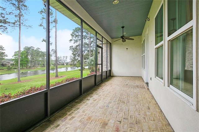 unfurnished sunroom featuring a water view and ceiling fan