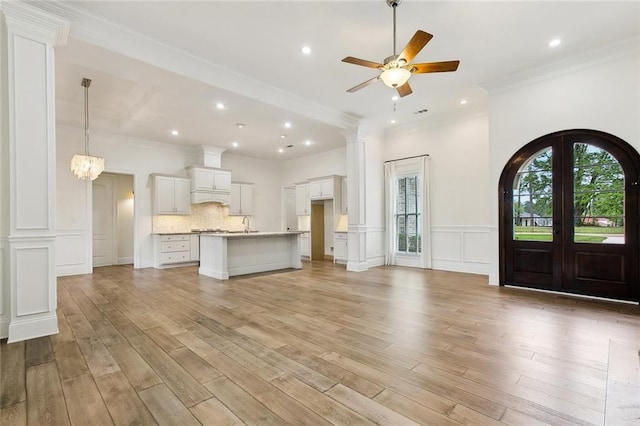 unfurnished living room with a decorative wall, ceiling fan, light wood-style floors, crown molding, and recessed lighting