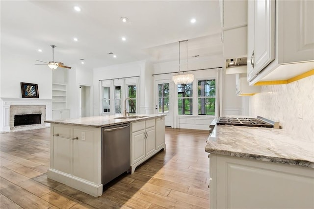 kitchen featuring light wood-style flooring, ceiling fan with notable chandelier, stainless steel dishwasher, and a sink