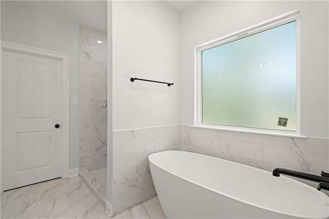 full bath with a freestanding bath, tile walls, a marble finish shower, a wainscoted wall, and marble finish floor