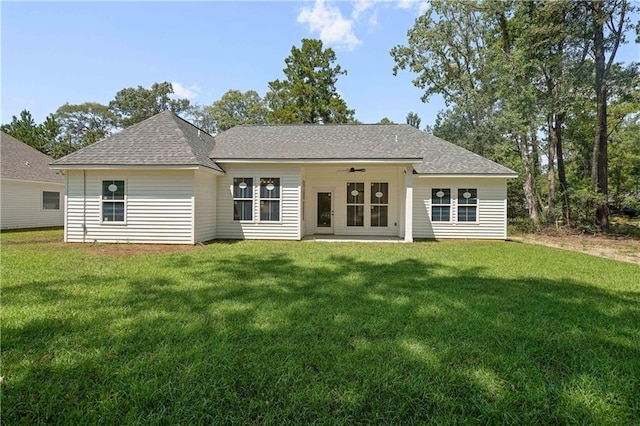 rear view of property with a yard, ceiling fan, and a shingled roof