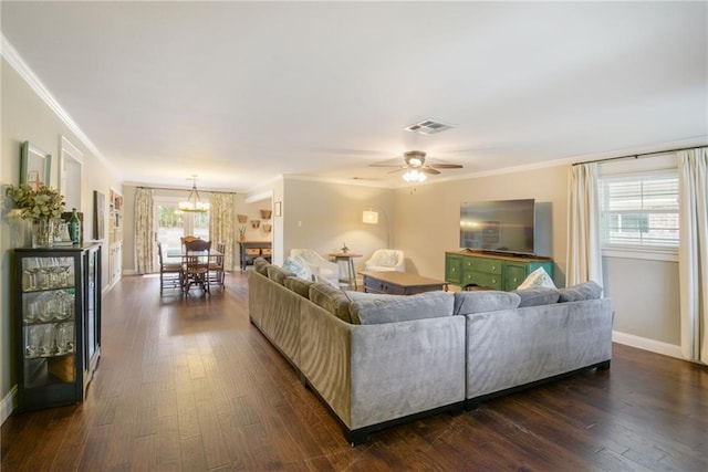 living room featuring ornamental molding, dark wood-style flooring, baseboards, a chandelier, and ceiling fan